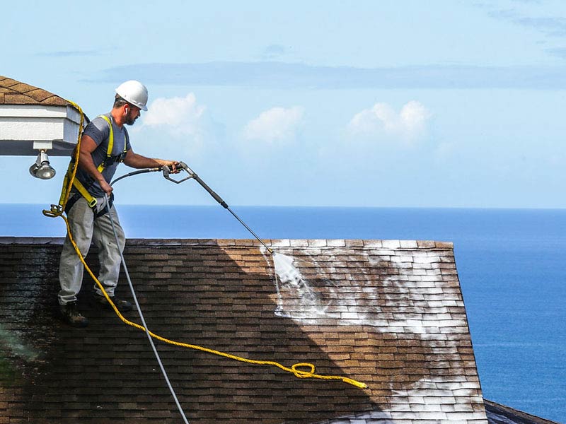 Close-up of a worker spraying a roof with Greener Shingles